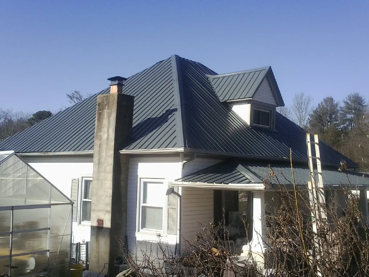 Dark blue standing seam metal roof on a white farmhouse with dormer — Slate & Tile Roof Repair by Roofing Brothers in Hollidaysburg