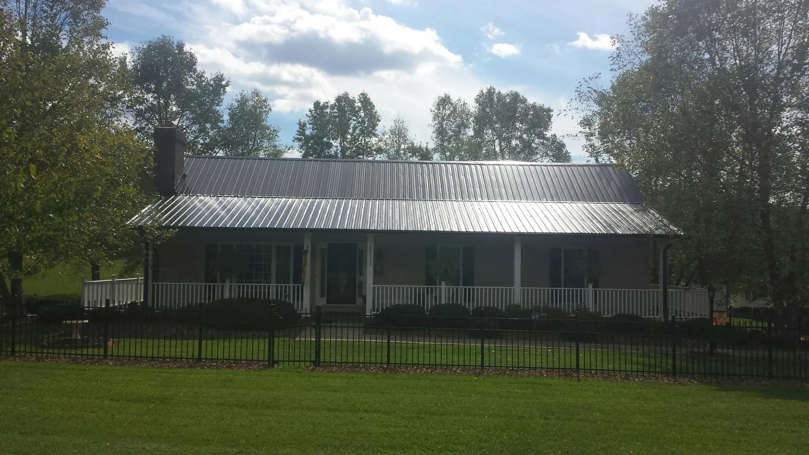 Gray metal roof on a brick ranch with a full width front porch — Gutter Guard Installation work by our crew in Hollidaysburg