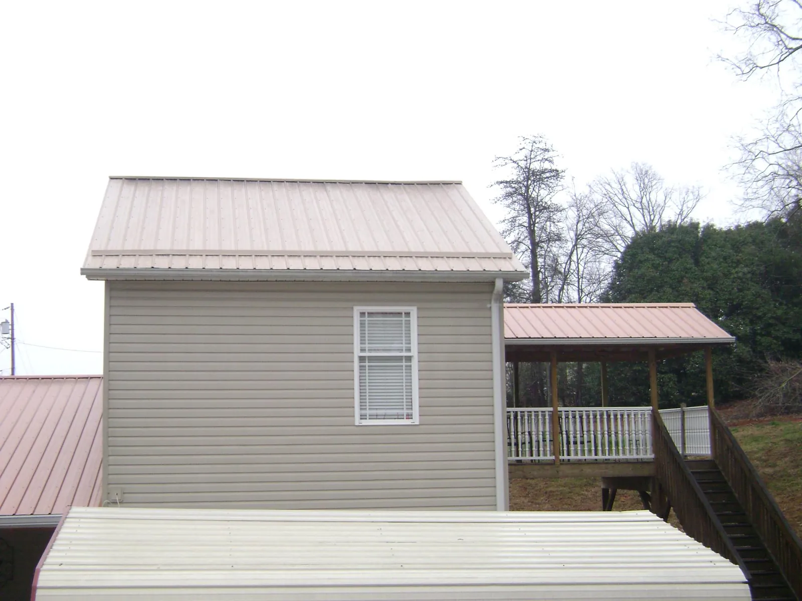 Tan metal roofs on a two story addition and attached porch, from a Roof Replacement job in Hollidaysburg