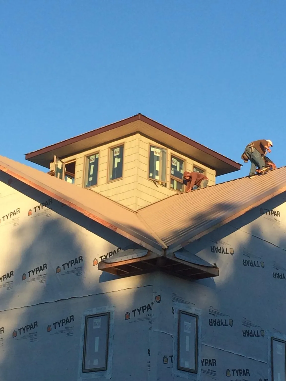 Roofers working around a rooftop cupola on a new metal roof at sunset — Roof Waterproofing in Hollidaysburg by Roofing Brothers